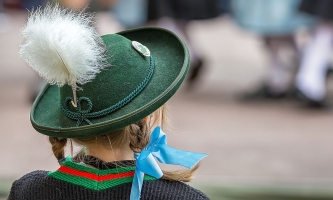 Mädchen in Tracht schaut einer Tanzgruppe zu