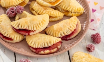 Quarktaschen mit roter Füllung und einzelne Himbeeren auf Schale