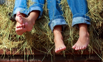 Kinderfüße in Jeans auf Heuboden