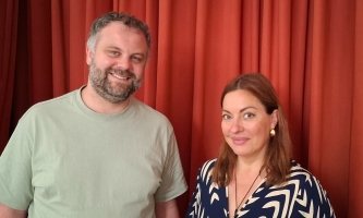 Christian Huber und Julia Dahmen lächeln vor einem roten Vorhang in die Kamera.