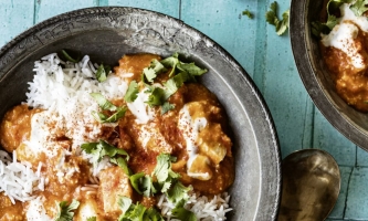 Schüssel mit Paneerwürfeln, Tomatensauce, Kräutern und Reis