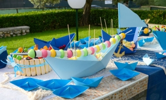 Gartentisch mit bunter Deko mit Papierschiffen und Süßigkeiten