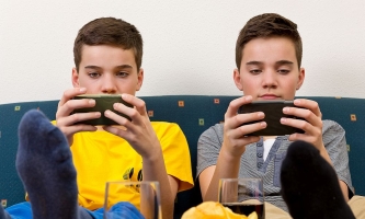 zwei Jungen sitzen auf Sofa und schauen in ihre Handys