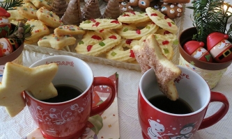 Plätzchen und Tassen mit weihnachtlicher Dekoration 