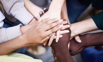 Jugendliche unterschiedlicher Hautfarbe halten Hände übereinander 
