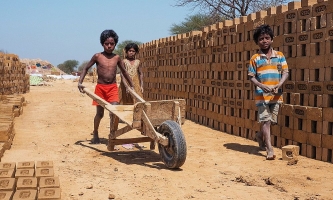 Kinder mit Schubkarre auf Ziegelfeld in Indien 