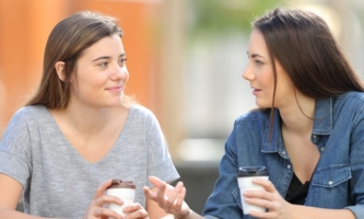 zwei Schwestern unterhalten sich draußen und trinken Kaffee