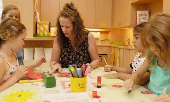 Kinder und Pädagogin an Basteltisch 