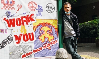 Junger Mann steht vor Wand mit bunten Aufschriften des Projekts Work4 You. 
