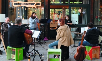 Band vor Gebäude, junge Frau am Mikrofon singt 