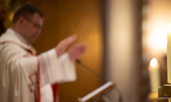 Priester mit ausgebreiteten Armen am Ambo 