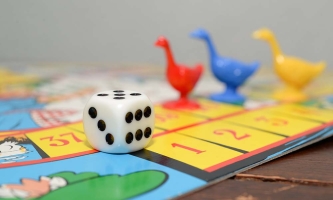 Brettspiel mit einem Würfel und drei Spielfiguren