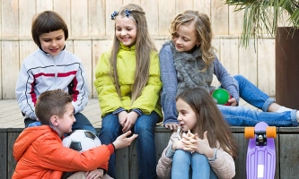 Eine Gruppe von Kindern sitzt draußen und unterhält sich.