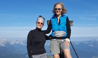 Die Freundinnen Angelika und Heike stehen vor einem Gipfelkreuz.