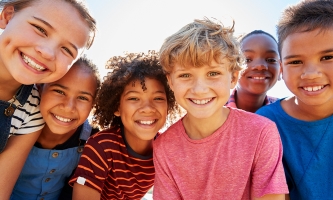 Mehrere Kinder stehen eng beieinander und strahlen in die Kamera.