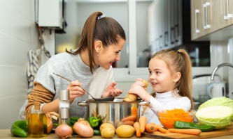 Mutter und Tocher kochen zusammen eine Suppe.