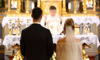 Brautpaar in Kirche während Priester am Altar betet 