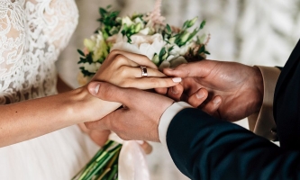 Der Bräutigam steckt der Braut den Ring an den Finger 