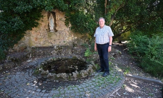 Otto Hamsa steht draußen vor einer Marienstatue.