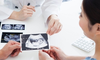werdende Eltern bei Arztgespräch mit Ultraschallbildern