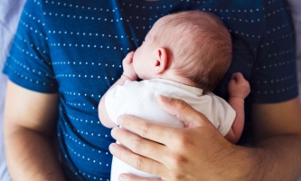 Baby liegt auf Bauch des Vaters