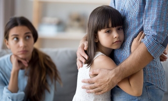 Kind umarmt Vater, während Mutter auf der Couch sitzt 