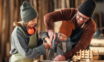 Mutter, Vater, Kind in Werkstatt mit Bohrmaschine