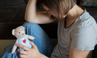 Frau trauert mit Stofftier in der Hand