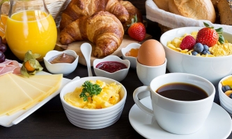 Frühstückstisch mit Obst, Saft, Kaffee, Brötchen, Marmelade und Eiern 