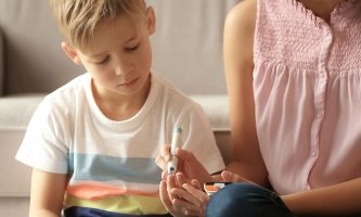 Junge und Mutter messen Insulin am Finger des Kindes 