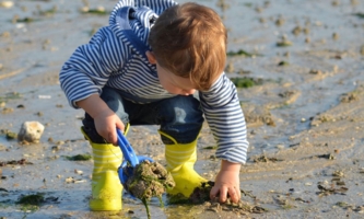Kind spielt am Strand mit Sand 