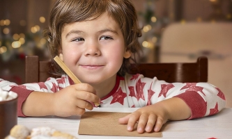 Junge schreibt Wunschzettel für Weihnachten und denkt über das Christkind nach 