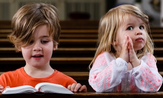 zwei Kinder sitzen in Kirchenbank