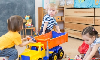 Kinder streiten in der Kita um einen Spielzeuglastwagen 