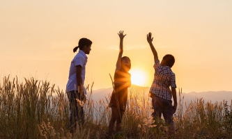 Kinder spielen auf einer Wiese im Sonnenuntergang 