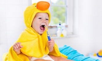 Kleinkind im Badetuch mit Zahnbürste 