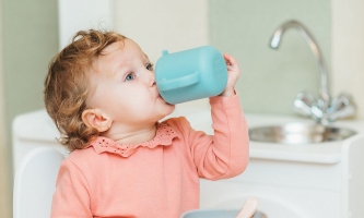 Kleinkind trinkt aus Plastikbecher 