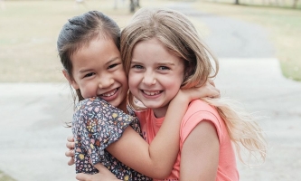 Zwei Mädchen umarmen sich und lachen fröhlich 