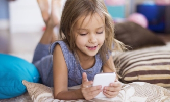 Mädchen liegt auf dem Boden und schaut ins Smartphone 