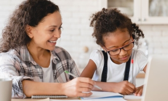 Mutter und Kind bei Hausaufgaben mit augeklapptem Notebook 
