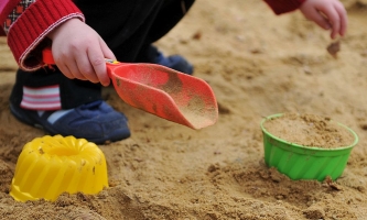 Kind spielt im Sandkasten mit Spielzeug 