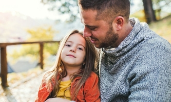 Vater und Tochter sitzen im Gespräch in der herbstlichen Natur 