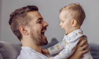 Vater und Baby lachen sich an und sagen Ah