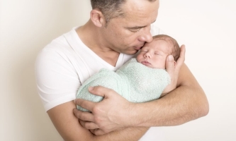 Vater hält schlafenden Säugling liebevoll im Arm