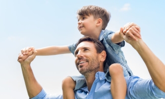 Vater froh mit Sohn auf seinen Schultern 