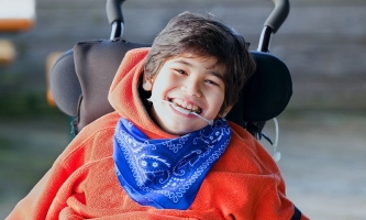 Junge mit Behinderung im Rollstuhl lacht froh 