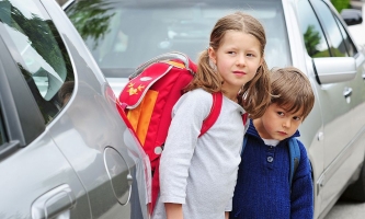 zwei Kinder zwischen Autos wollen die Straße überqueren