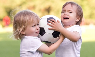 Zwei Kinder streiten sich um einen Ball 