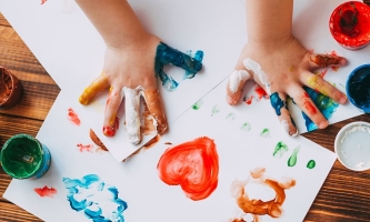 Kreative Kinderhände mit Farben malen bunte Bilder auf Papier