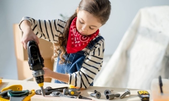 Mädchen an Werkbank mit Bohrmaschine 